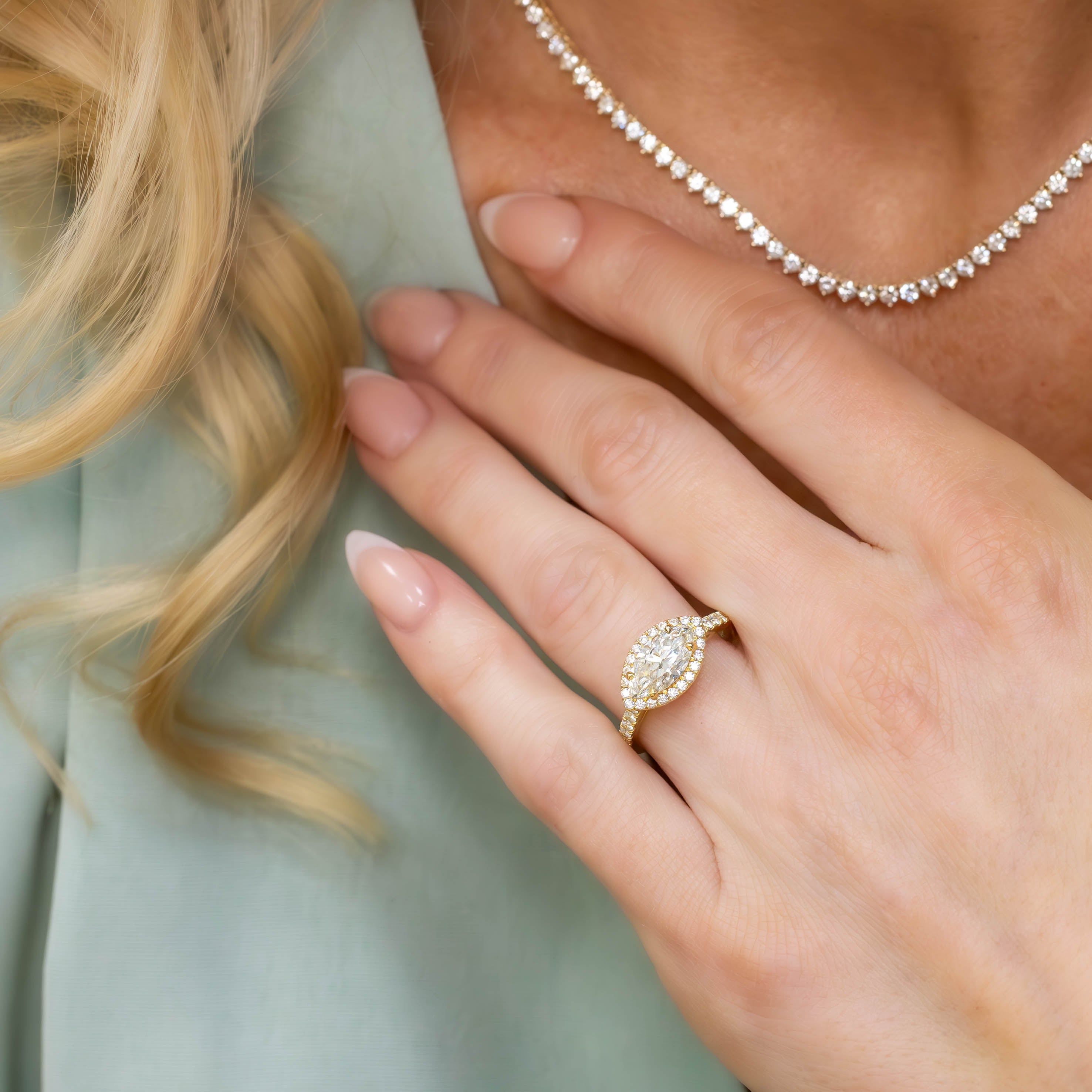 close up of Kate 18K Yellow Gold East West Marquise Diamond Halo Ring on a hand