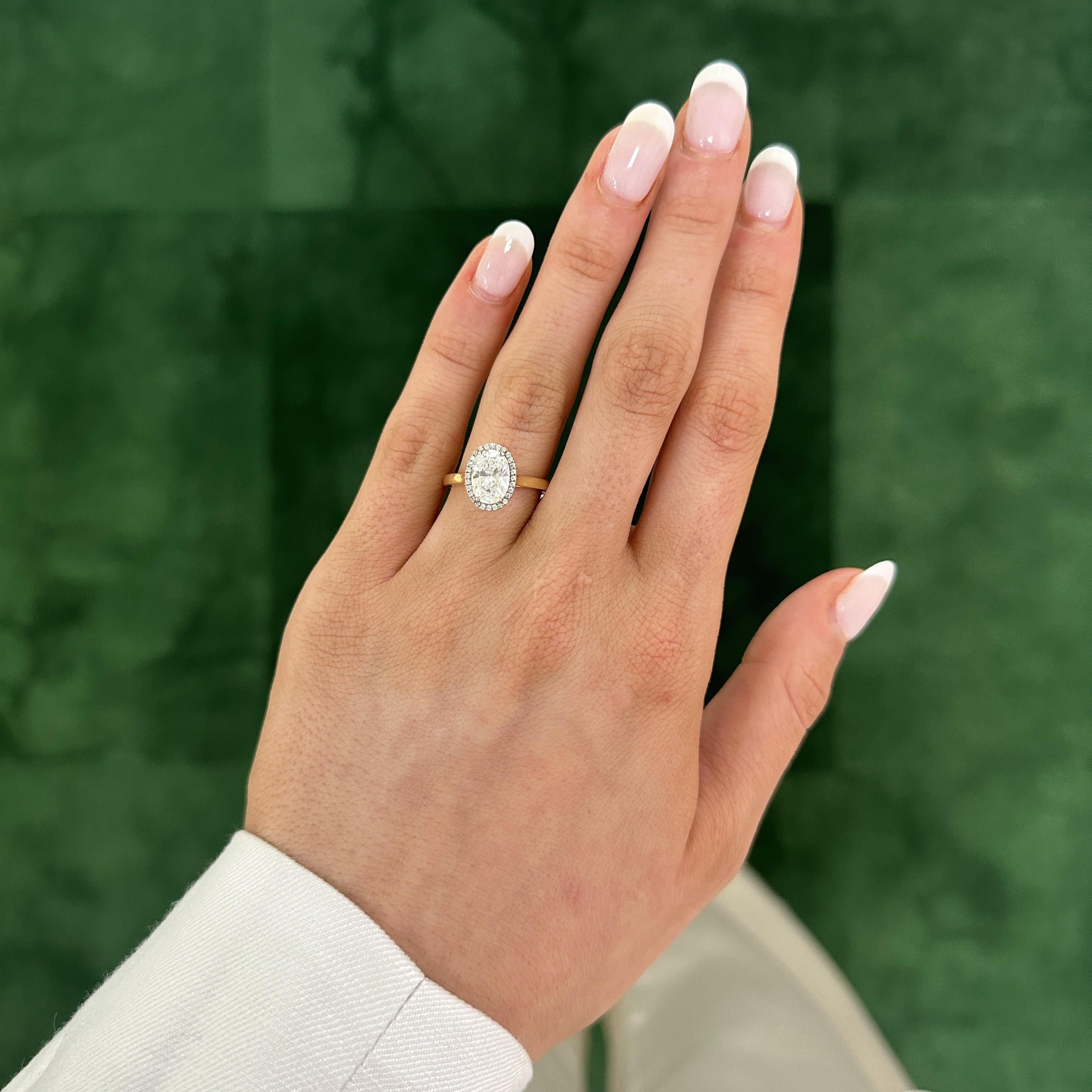 woman wearing our Taylor 18K Yellow Gold Oval Diamond Halo Ring on her hand